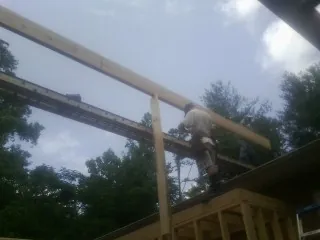 Carpenter setting a ridge beam over a new addition frame — Ice Dam Removal by Roofing Brothers in Fisher