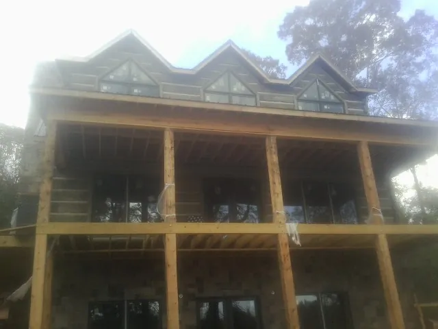 Dormers and porch framing on a large log home under construction — Roof Coating work by our crew in Fisher