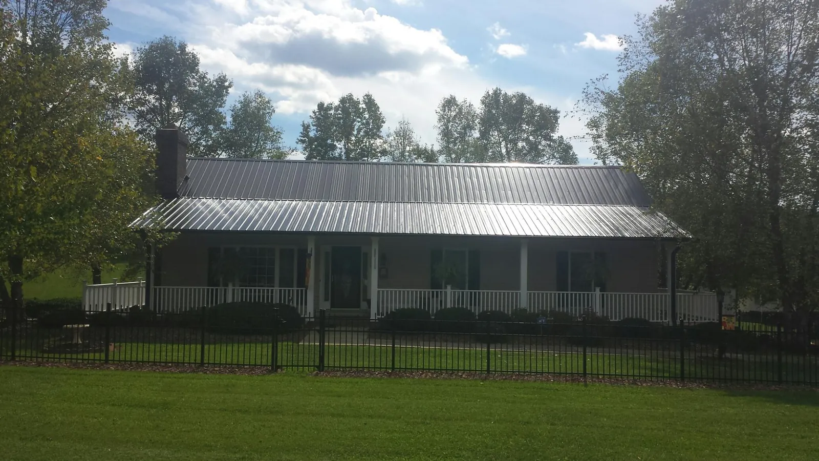 Gray metal roof on a brick ranch with a full width front porch — Gutter Guard Installation work by our crew in Fisher