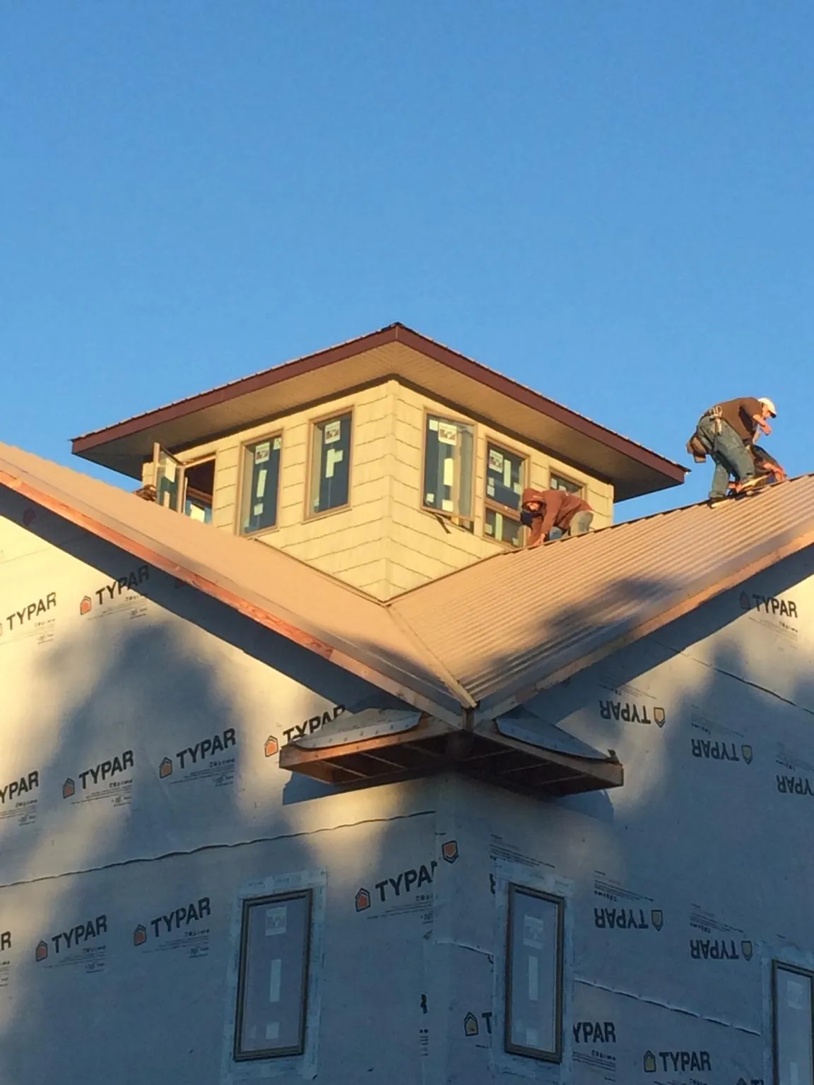 Roofers working around a rooftop cupola on a new metal roof at sunset — Roof Waterproofing in Fisher by Roofing Brothers